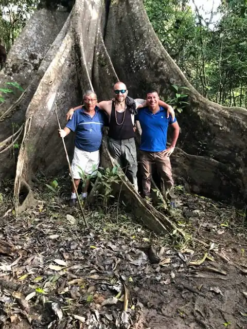 Al pie de un árbol gigante de la selva, con su hijo Antonio y un visitante.